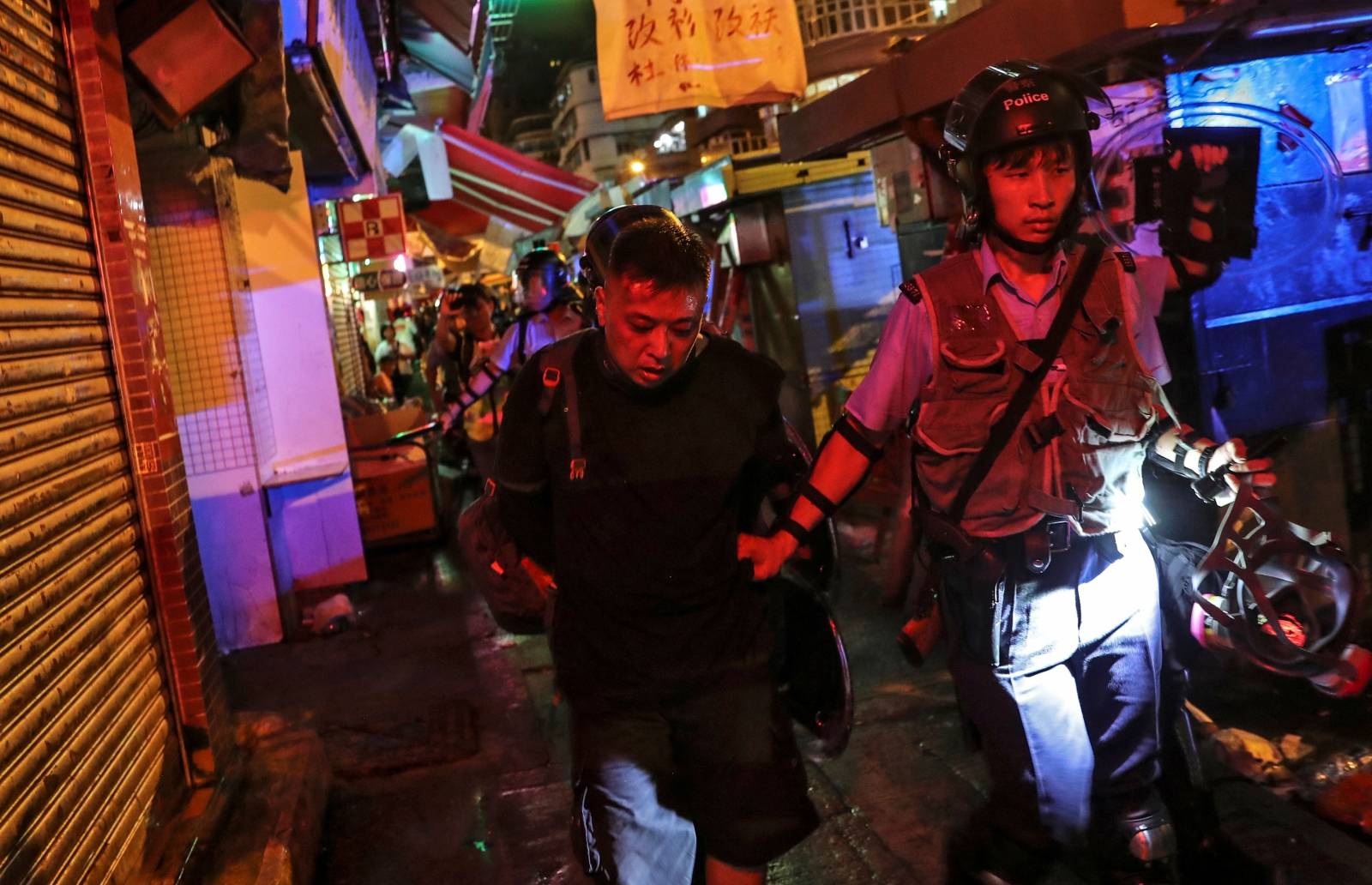 A demonstrator is escorted to a police van after being detained during a protest outside a police station in Hong Kong