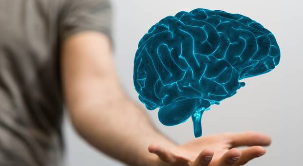 3D rendered hologram of a brain hovering over a real person’s palm.