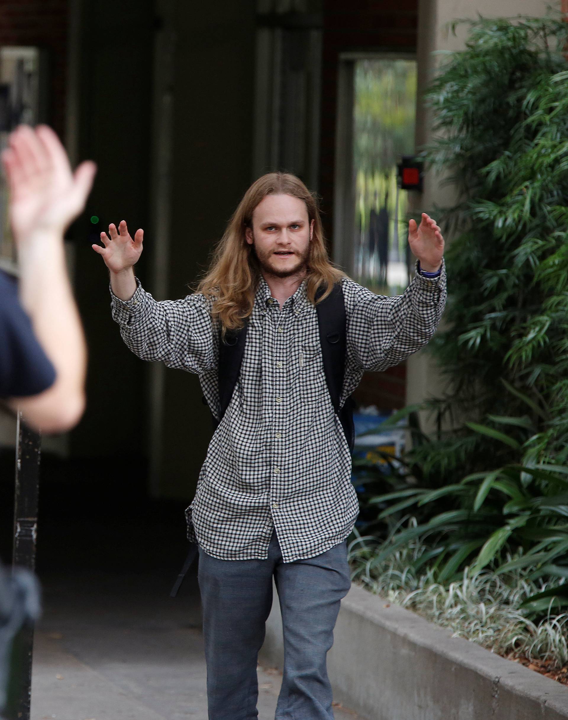 A police officer directs a person before searching him at the UCLA campus after it was placed on lockdown following reports of a shooter that left 2 people dead in Los Angeles, California