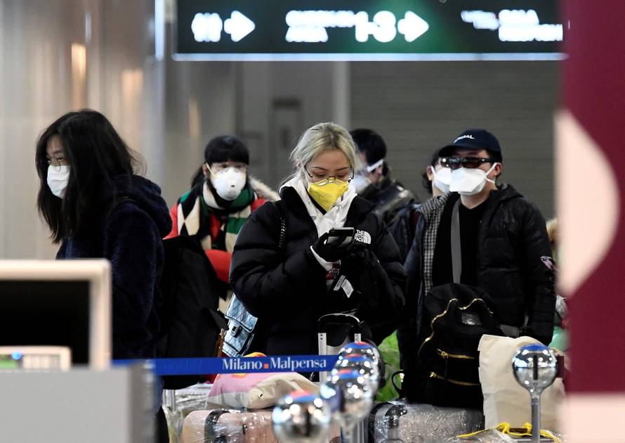 People wearing protective masks are seen at Malpensa airport near Milan