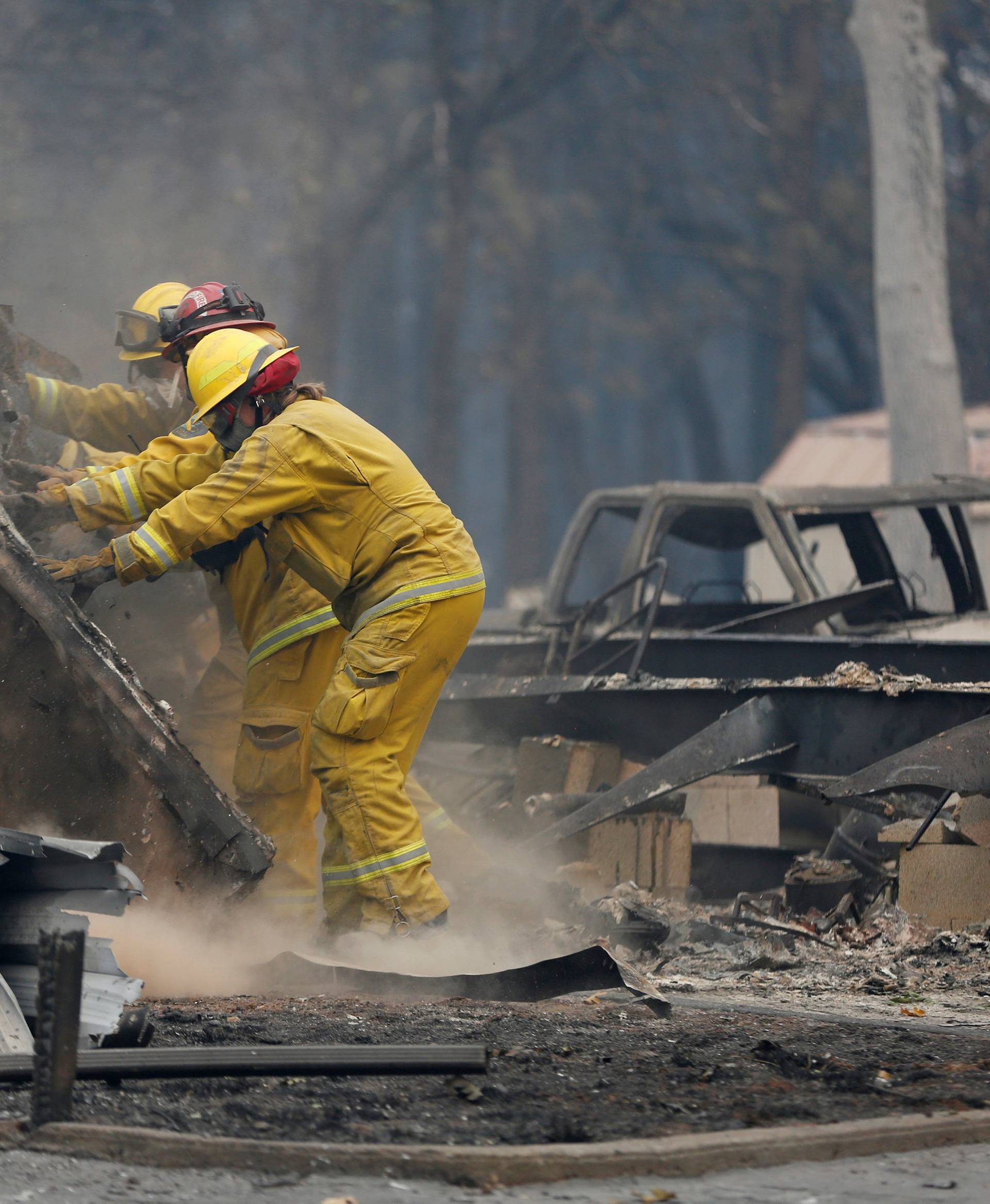 Cal Fire firefighters comb through a house destroyed by the Camp Fire in Paradise