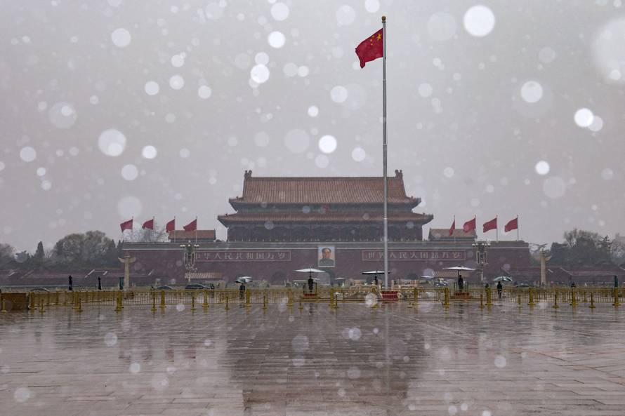Chinese national flag flutters near Tiananmen Gate amid snowfall before the opening sessions of the annual CPPCC