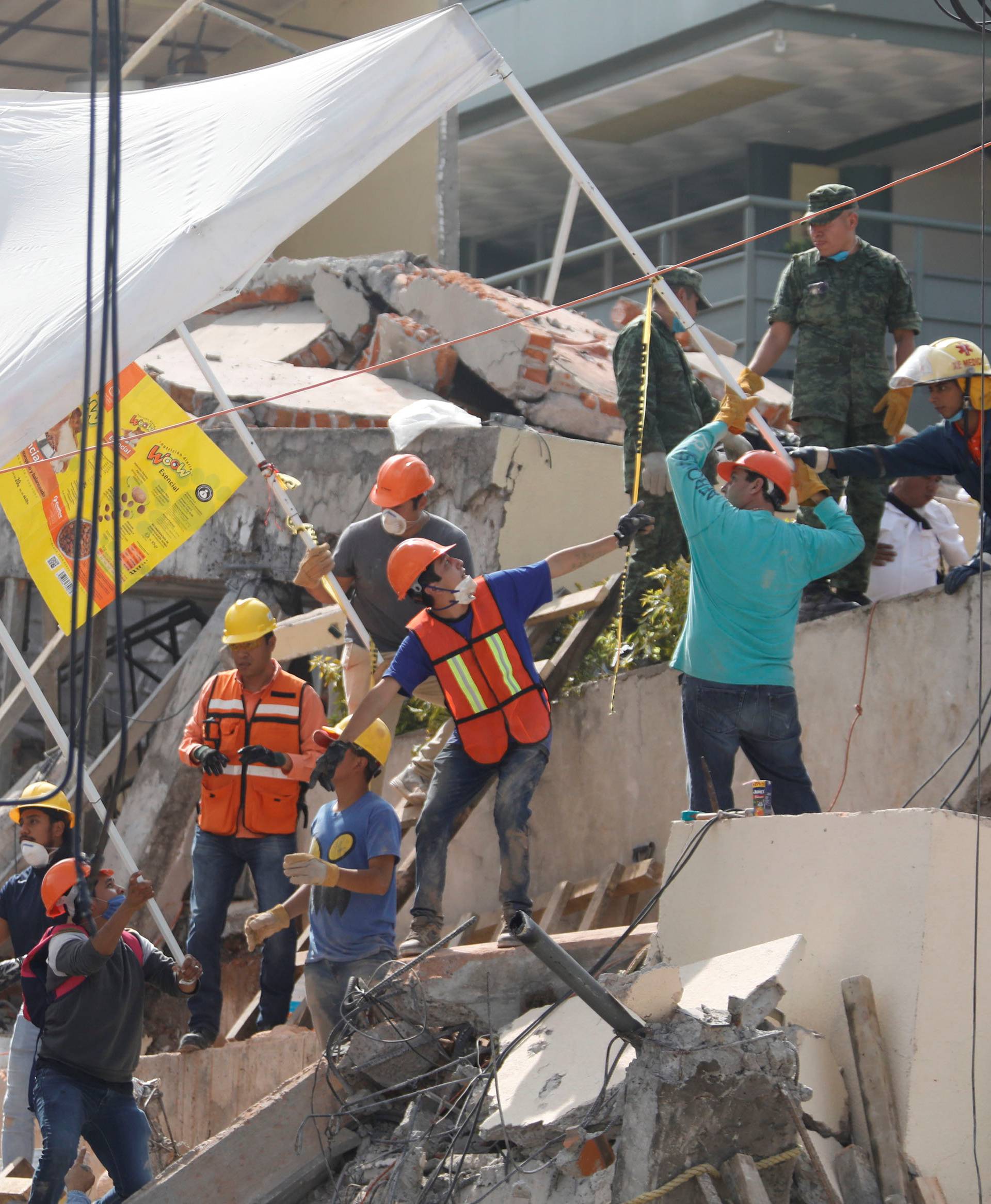 Rescue workers transport a tent as they search for students through the rubble at Enrique Rebsamen school after an earthquake in Mexico City