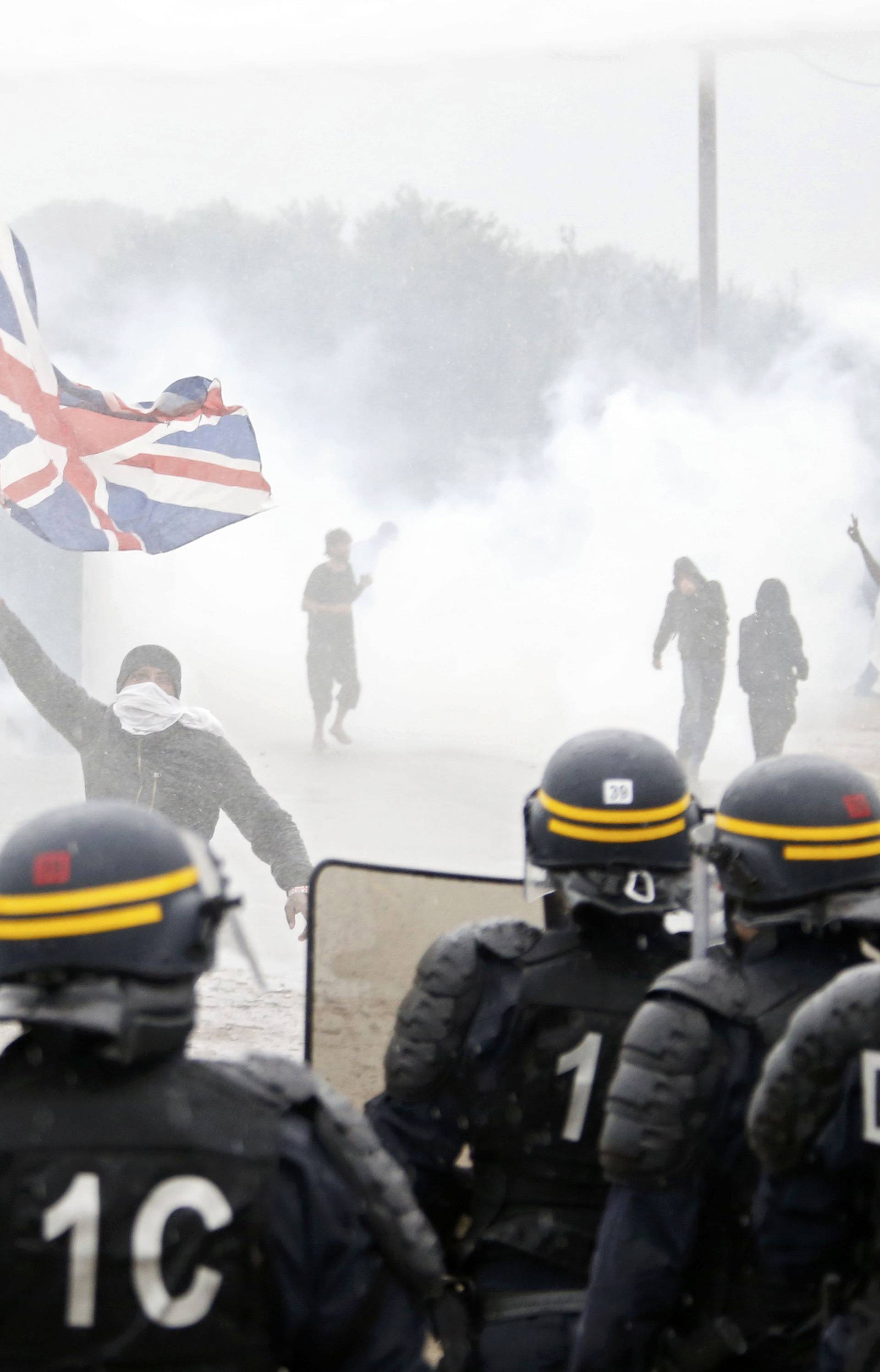 Tear gas fills the air as French riot police face off with demonstrators near the area called the "jungle" where migrants live in Calais