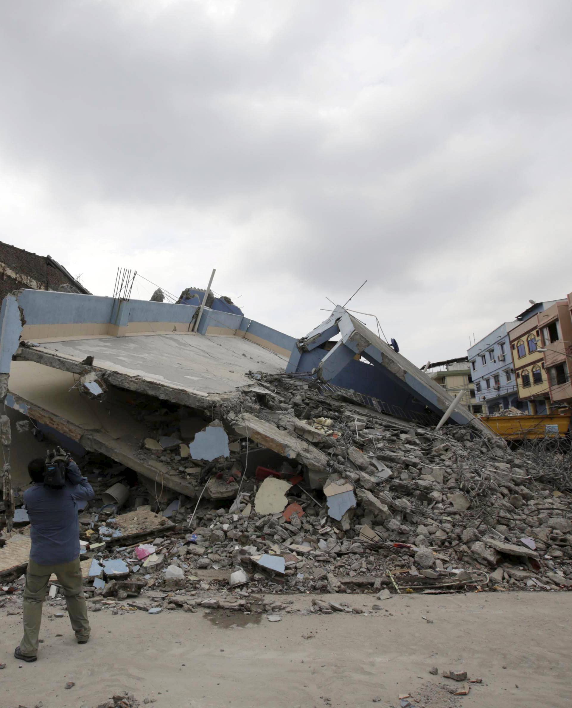 A television cameraman films a collapsed building in Guayaquil after an earthquake struck off the Pacific coast in Ecuador