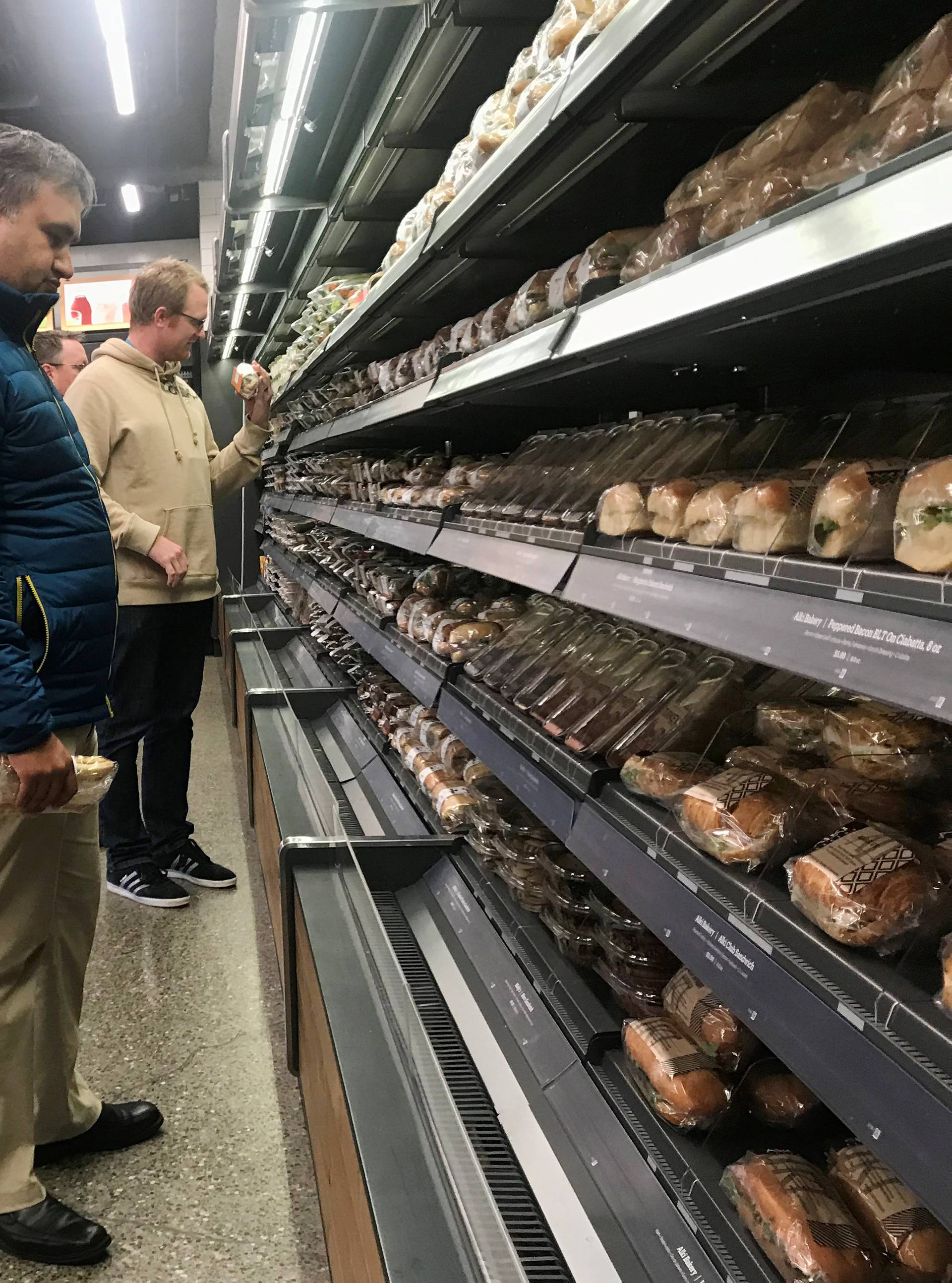 Customers browse packaged wraps, sandwiches and salads at Amazon's new "grab-and-go" store in Seattle