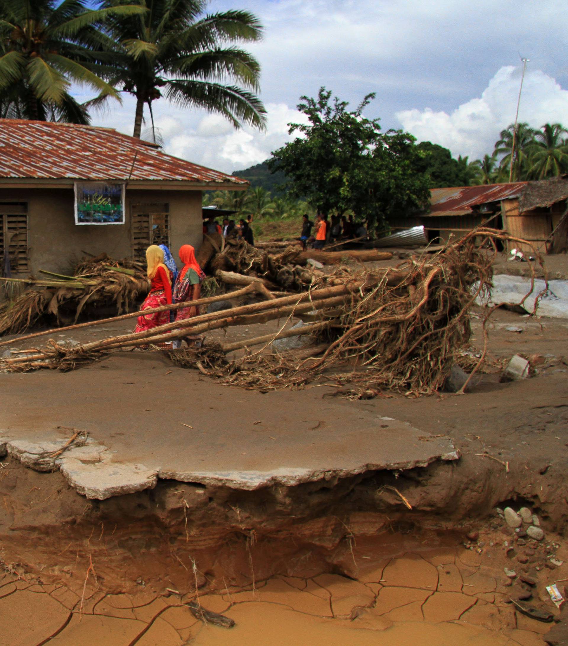 Residents walk in a village devastated by flash floods in Salvador, Lanao del Norte