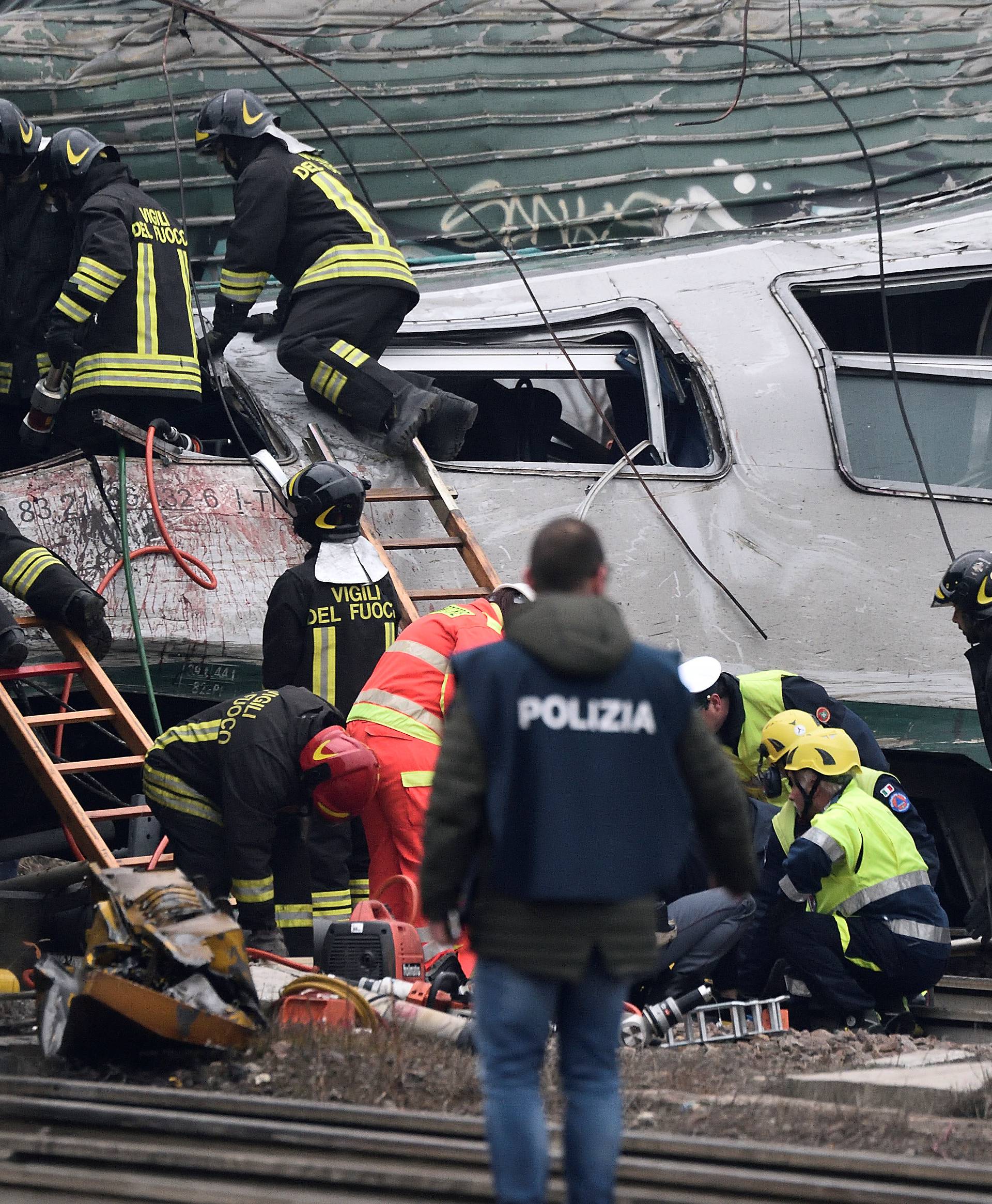 Fire fighters and police officers work around derailed trains in Pioltello, on the outskirts of Milan