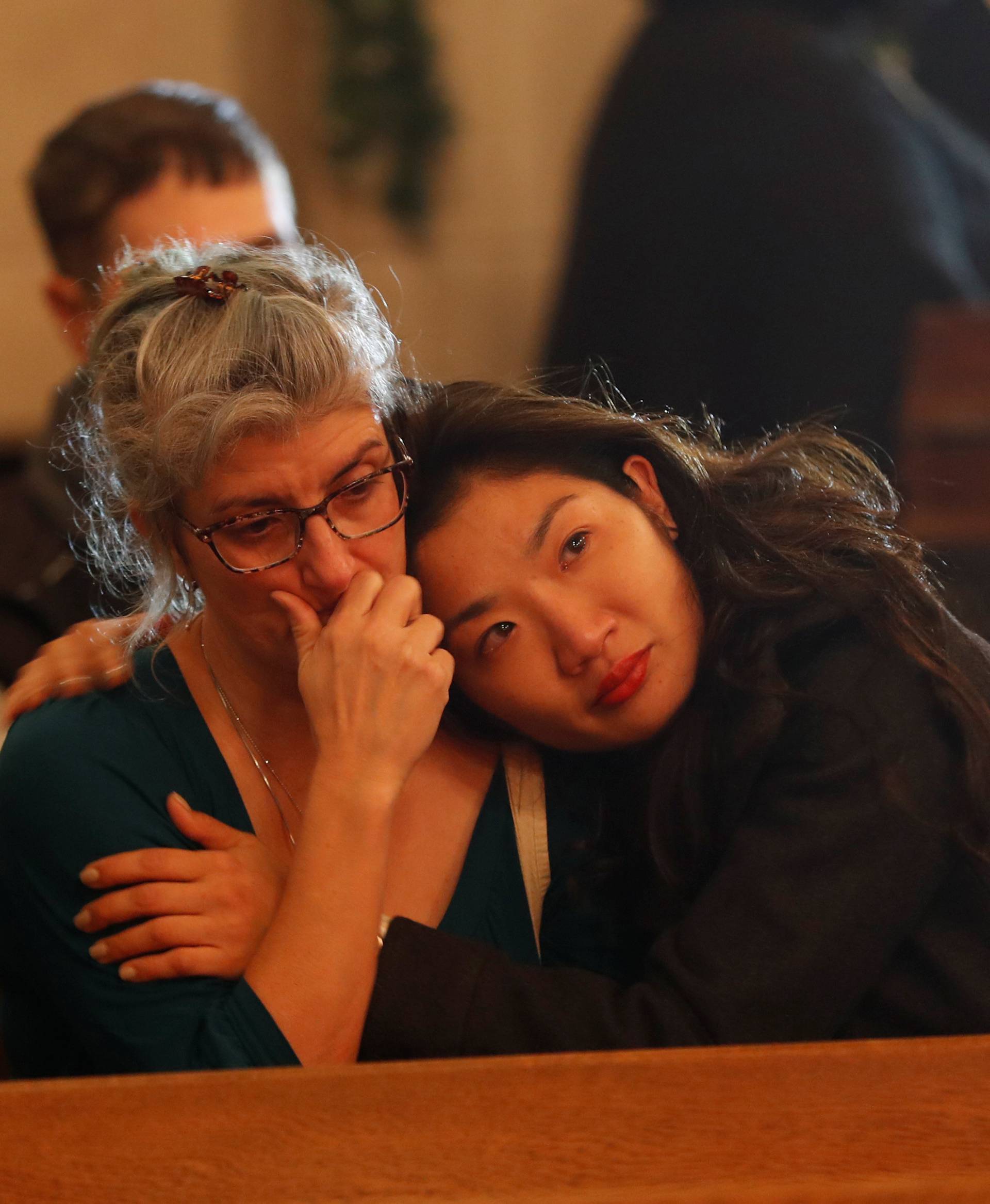 People embrace during a vigil at the Chapel of the Chimes for the victims of a fire in the Fruitvale district of Oakland