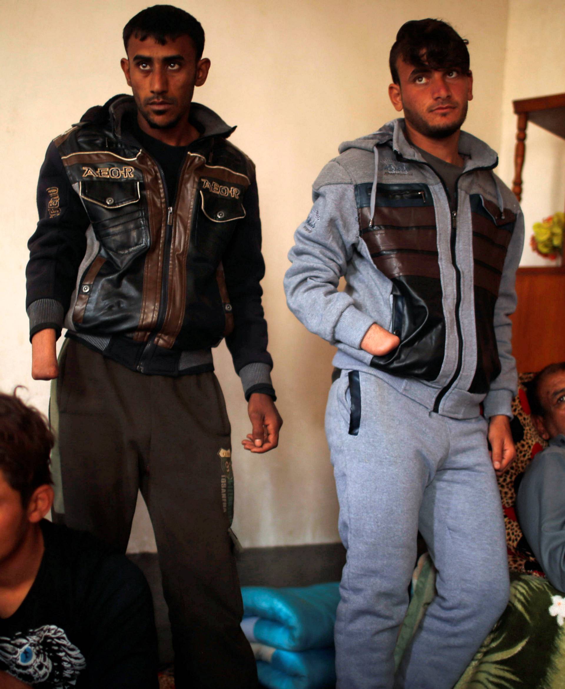 Azad Hassan and his brother Mohammad, whose hands were chopped off by Islamic State militants, stand beside their wounded father in a house at Nimrud village, south of Mosul