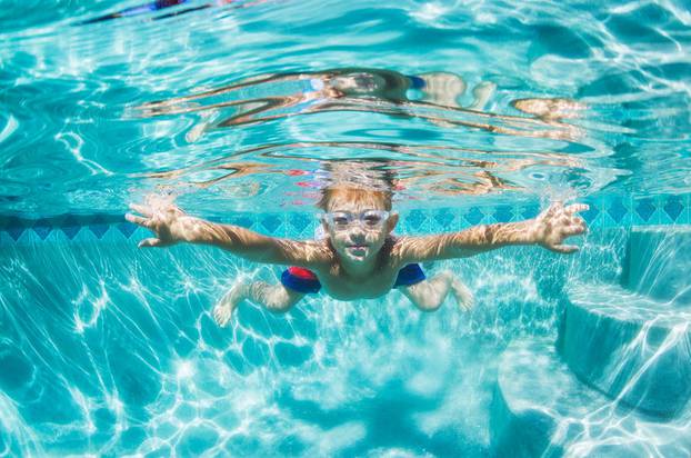 Young Boy Diving Underwater in Swimming Pool