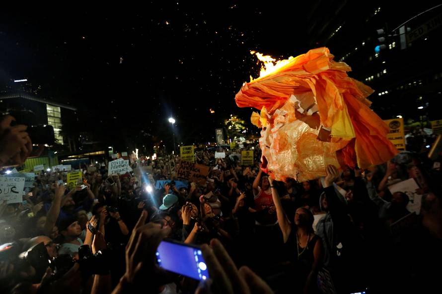 People hold a pinata which was lit on fire while protesting the election of Republican Donald Trump as the president of the United States in downtown Los Angeles