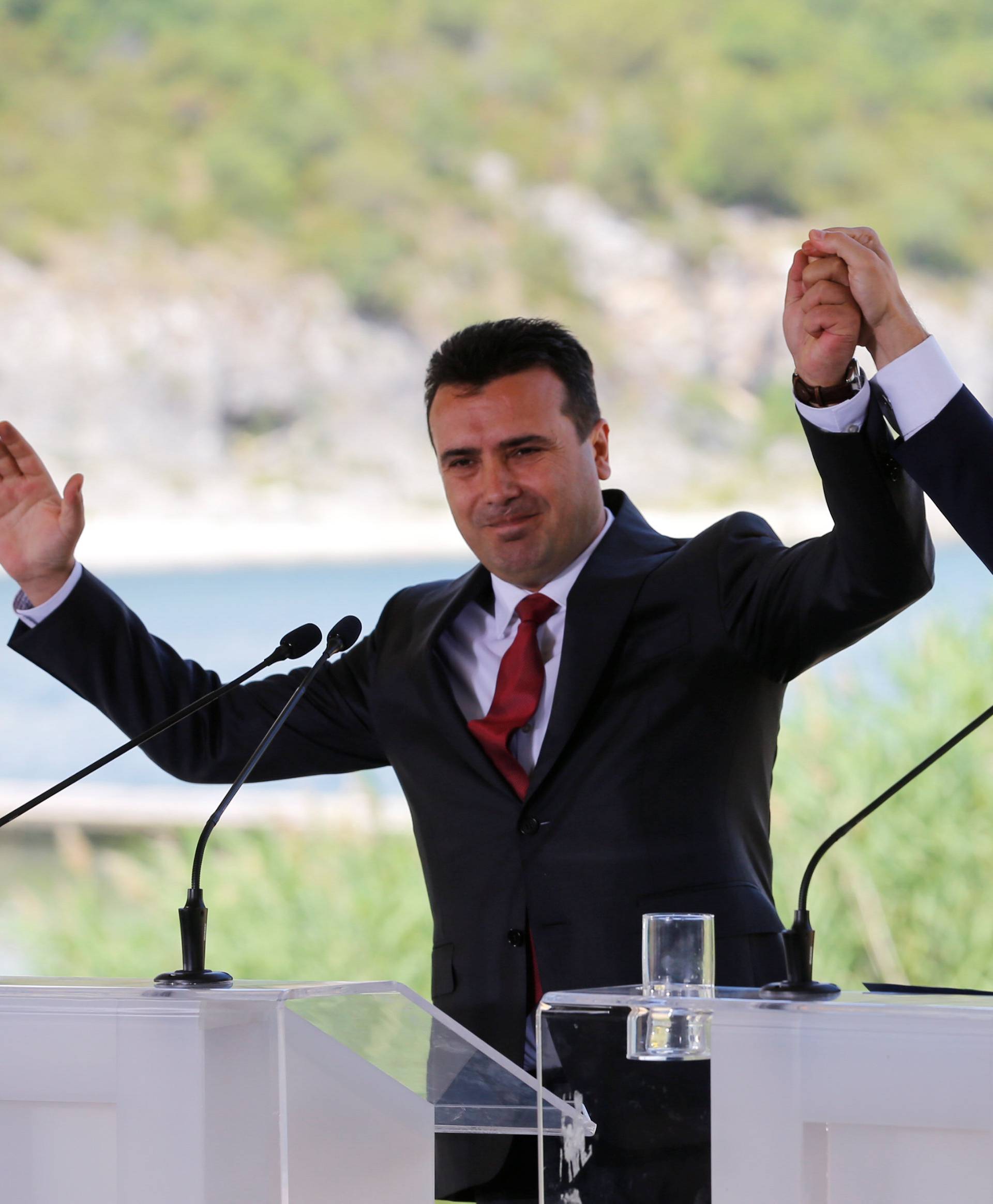 Greek Prime Minister Alexis Tsipras and Macedonian Prime Minister Zoran Zaev gesture before the signing of an accord to settle a long dispute over the former Yugoslav republic's name in the village of Psarades