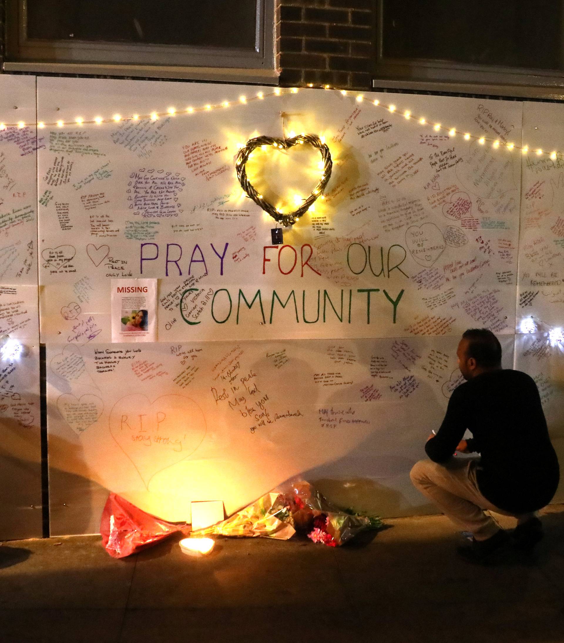 A man reads messages of condolence on a wall  near a tower block severely damaged by a serious fire, in north Kensington, West London