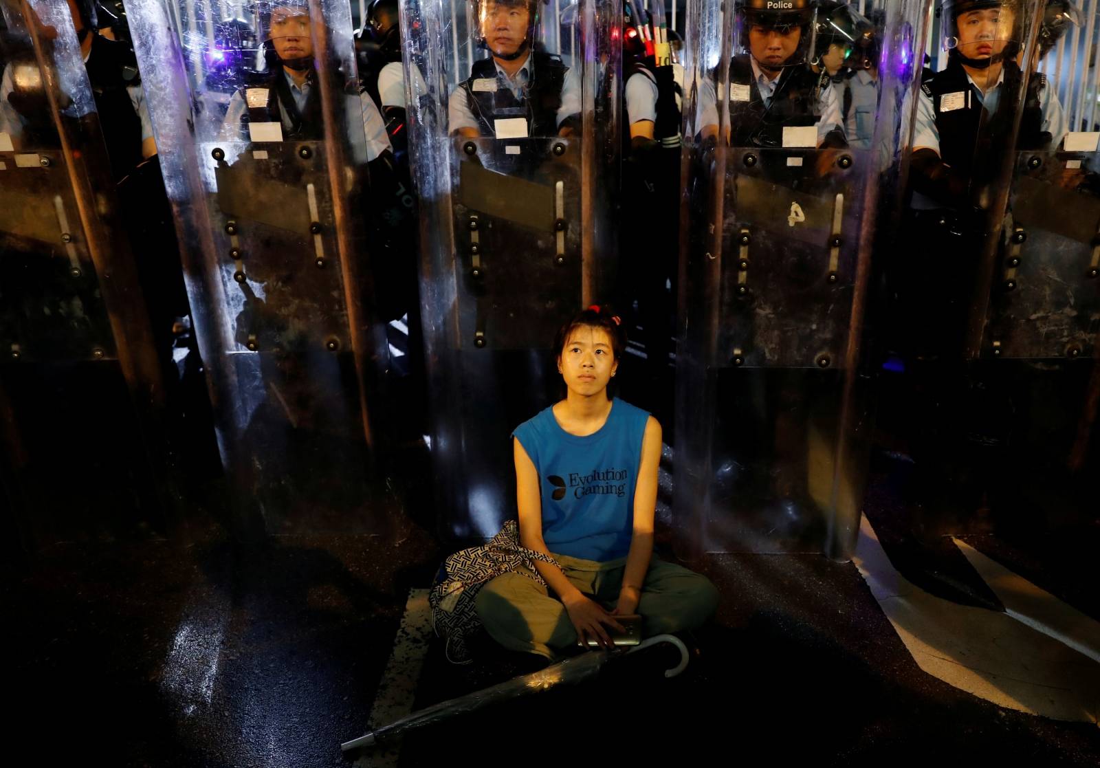 Demonstrator sits down in front of riot police during a demonstration to demand authorities scrap a proposed extradition bill with China, in Hong Kong