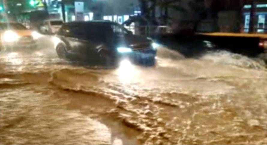A still image shows vehicles driving along a street in a settlement affected by floodwaters in Krasnodar Region