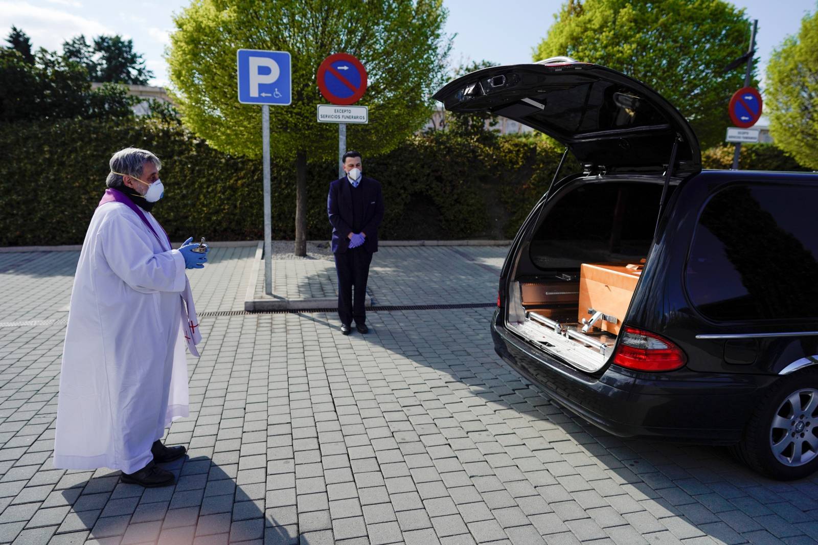 A priest gives a response in front the coffin of a woman who died of coronavirus disease (COVID-19), during partial lockdown to combat the coronavirus disease (COVID-19) outbreak in Madrid