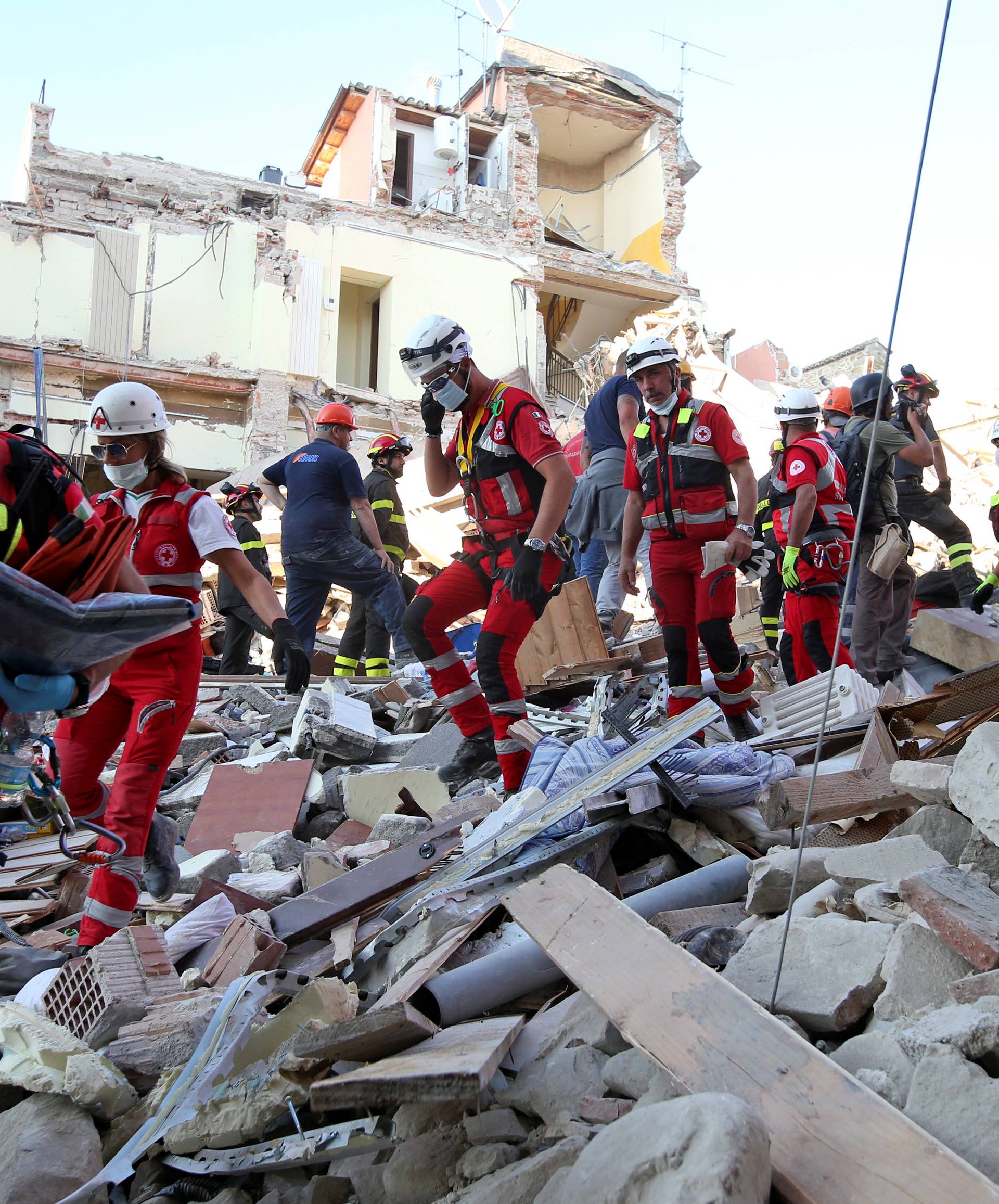Rescuers walk through rubble following the earthquake in Amatrice