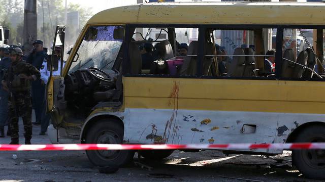 Afghan security forces inspect the damage of a minibus that was hit by a suicide attacker at the site of the incident in Kabul