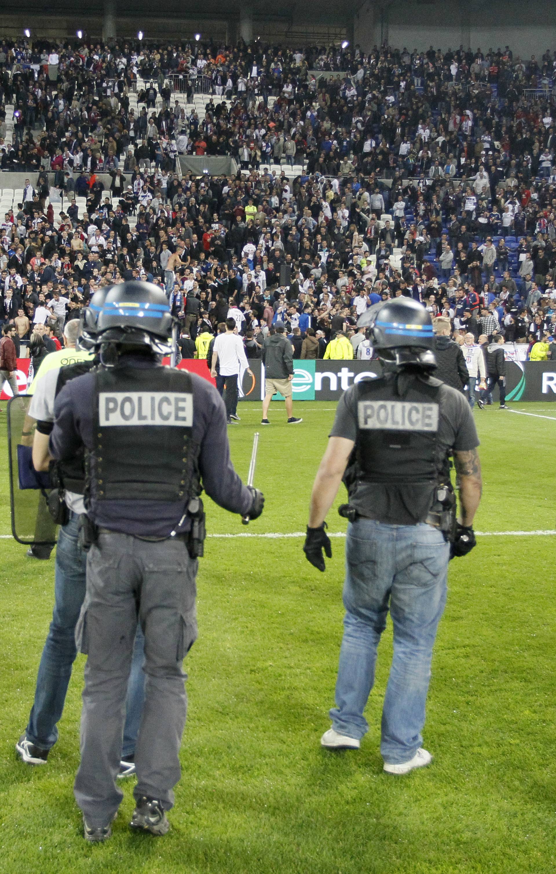 Police officers as Lyon fans invade the pitch and fans clash in the stands