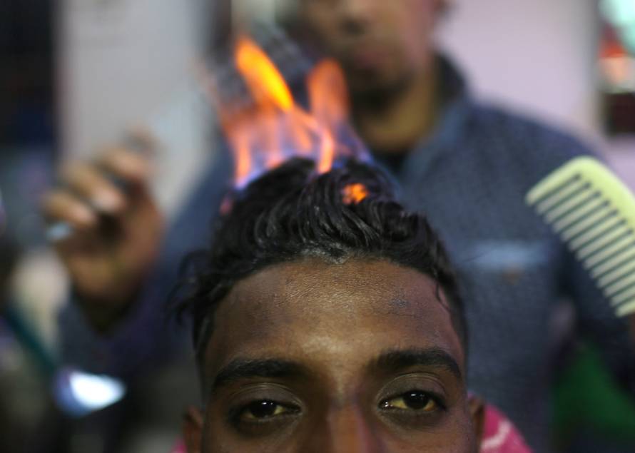 Palestinian barber Ramadan Odwan styles and straightens the hair of a customer with fire at his salon in Rafah, in the southern Gaza Strip