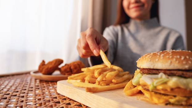 Closeup,Image,Of,A,Woman,Holding,And,Eating,French,Fries