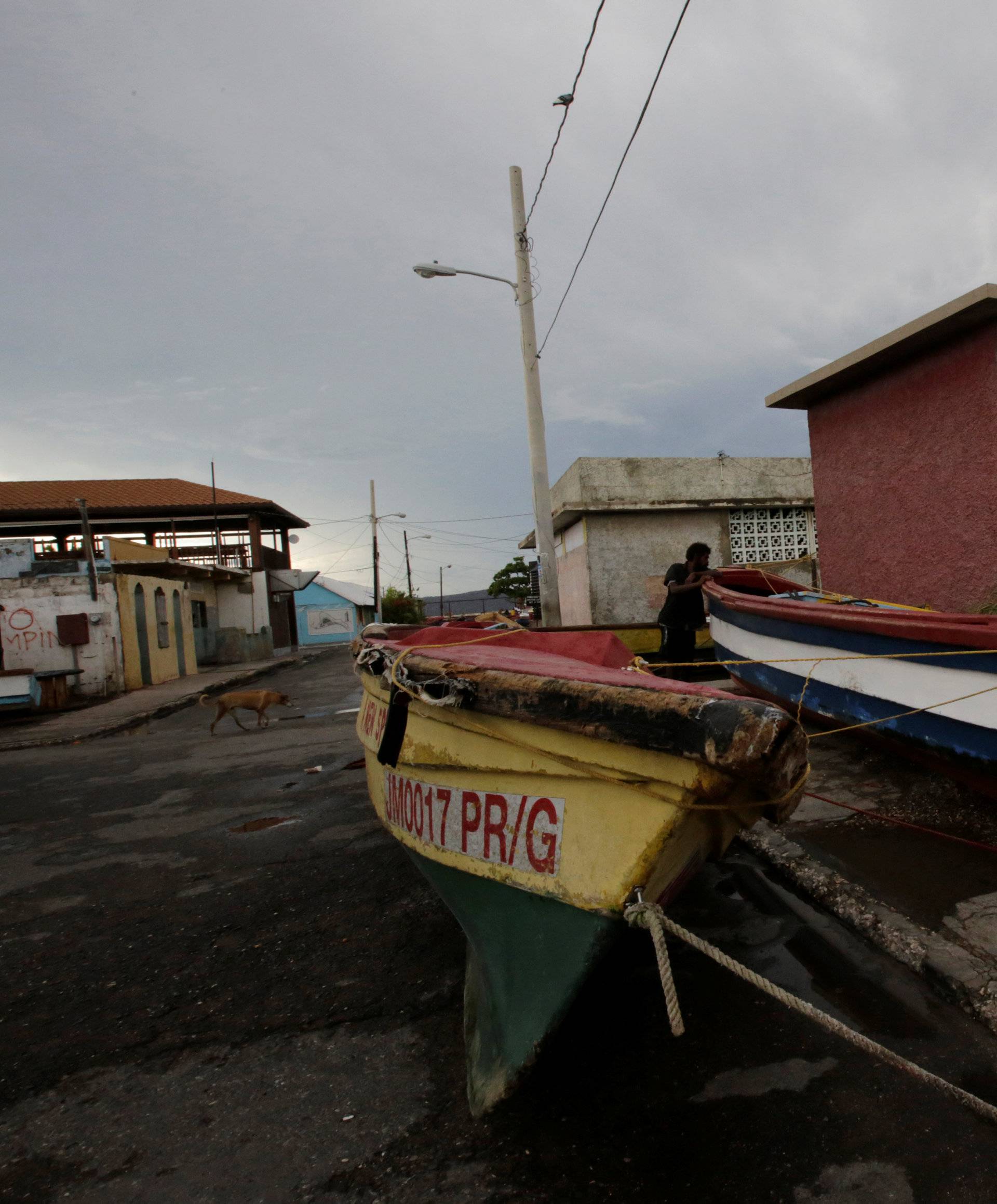 Boats are secured along a street as a resident looks on at Port Royal while Hurricane Matthew approaches in Kingston, Jamaica