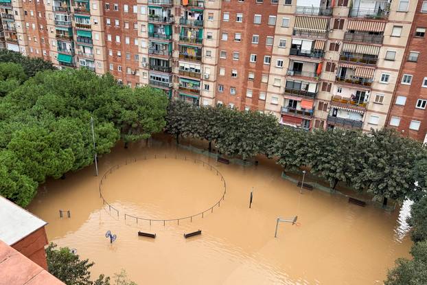 People look at the flooded playground following heavy rain in Sant Adria de Besos on the outskirts of Barcelona