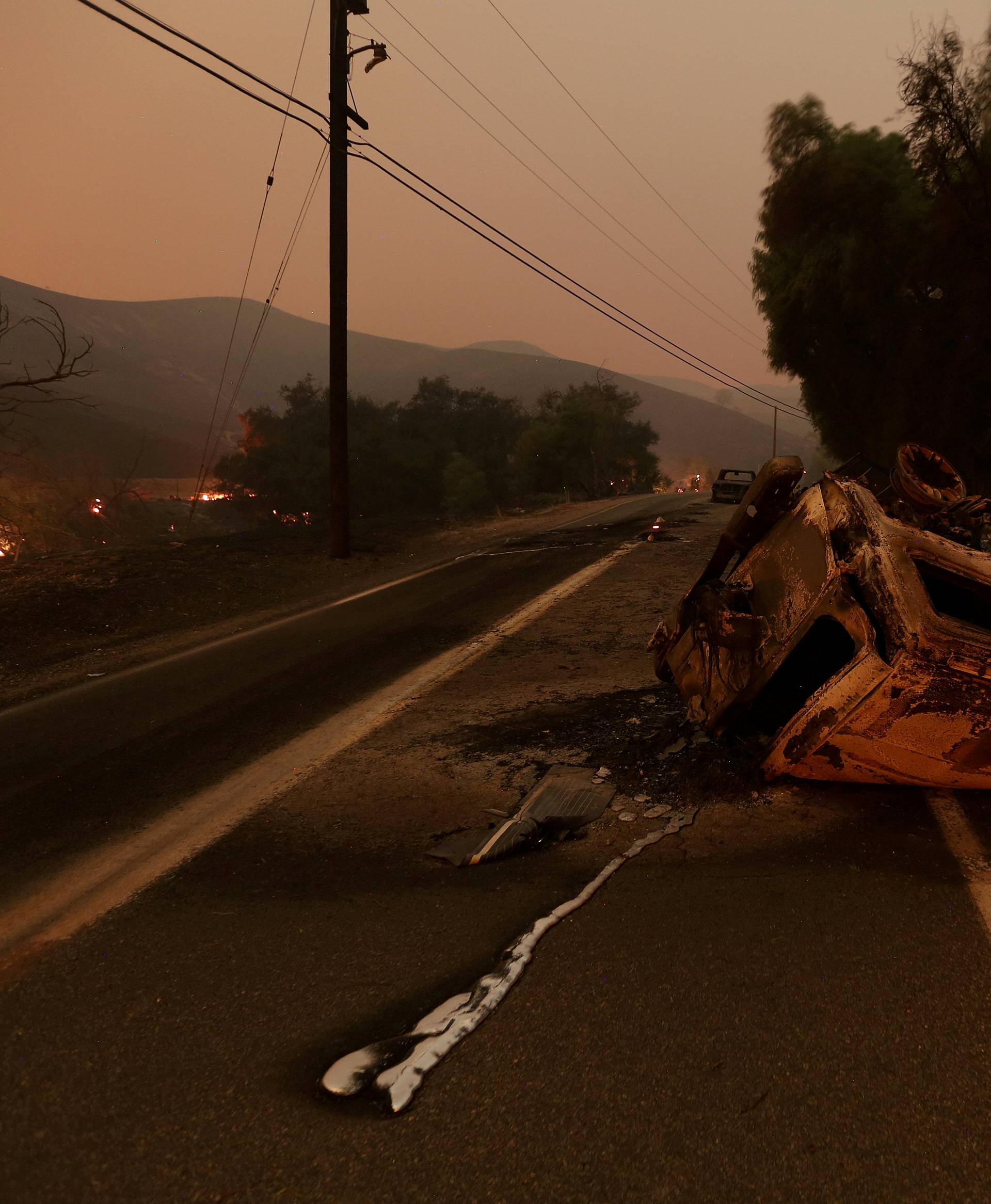 FILE PHOTO: The burned remains of crashed cars are seen at night on a country road as strong winds push the Thomas Fire across thousands of acres near Santa Paula