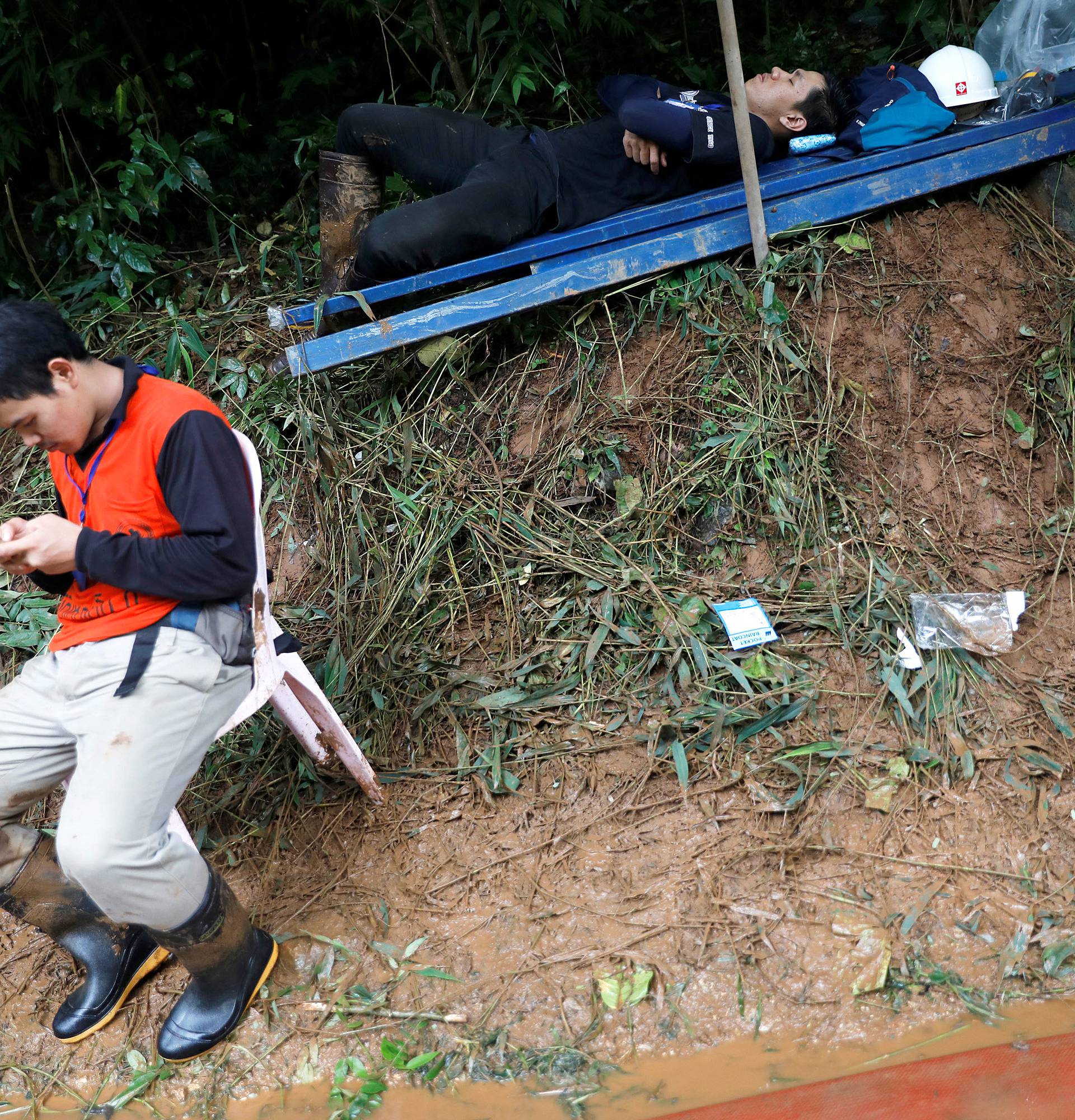 Rescue workers pass their time near the Tham Luang cave complex, as a search for members of an under-16 soccer team and their coach continues, in the northern province of Chiang Rai