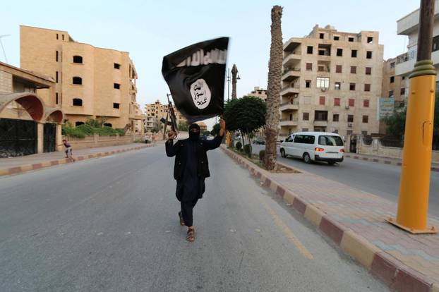 FILE PHOTO - A member loyal to the Islamic State in Iraq and the Levant (ISIL) waves an ISIL flag in Raqqa