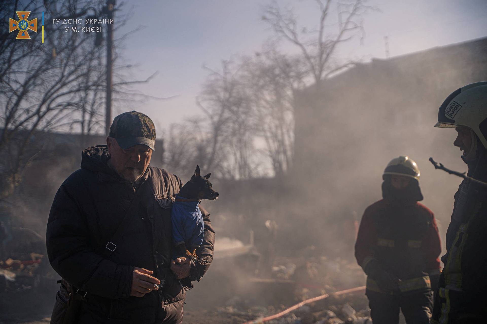 A man with a dog evacuates from a building damaged by shelling in Kyiv