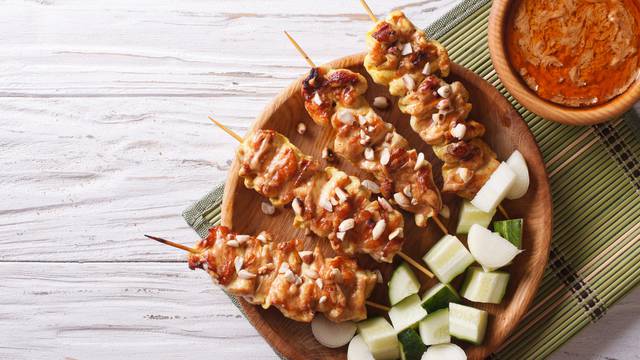 Chicken satay with a delicious peanut sauce. horizontal top view