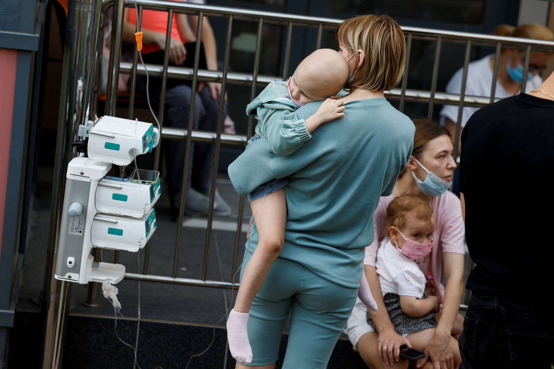 A woman carries a child near Ohmatdyt Children's Hospital that was damaged during Russian missile strikes, in Kyiv