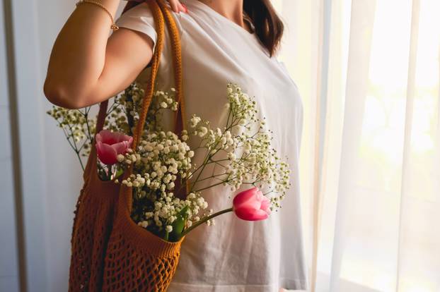 happy woman holding spring flowers on window