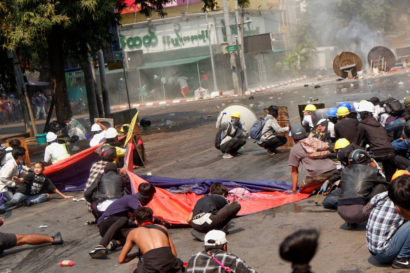 Protesters lie on the ground after police open fire to disperse an anti-coup protest in Mandalay