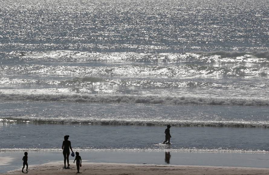 Holidays makers walk on the beach along the Atlantic Ocean as warm summer temperatures continue in Montalivet