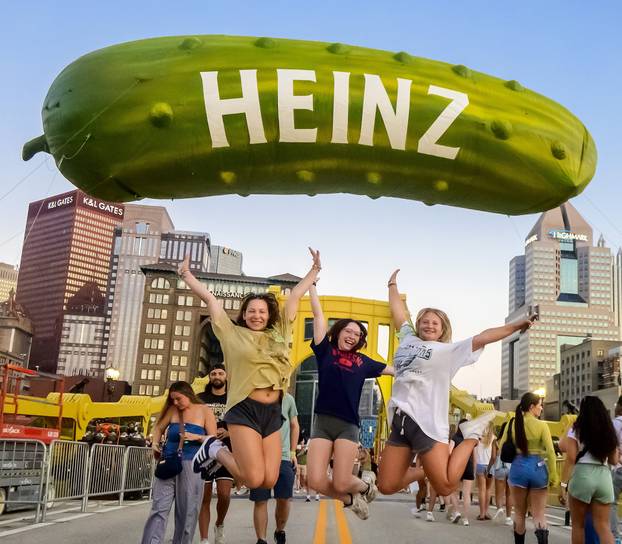 VIstors to Picklesburgh Jumping Under Giant Pickle in Pittsburgh
