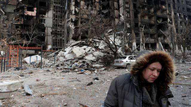 Nurse Svetlana Savchenko stands next to the destroyed building where her apartment was located in Mariupol