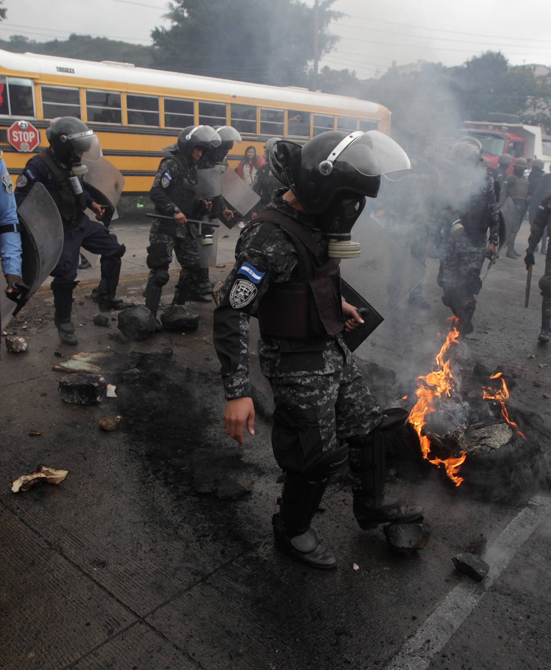 Security forces remove a burning barricade settled to block a road by supporters of Nasralla during a protest over a contested presidential election in Tegucigalpa