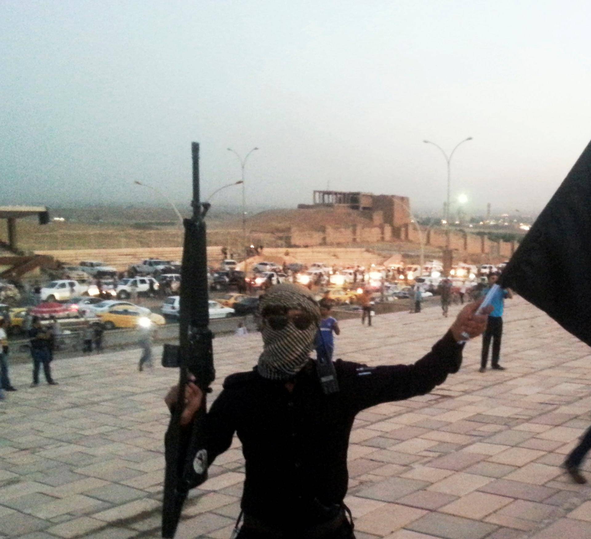 FILE PHOTO: A fighter of the ISIL holds a flag and a weapon on a street in Mosul