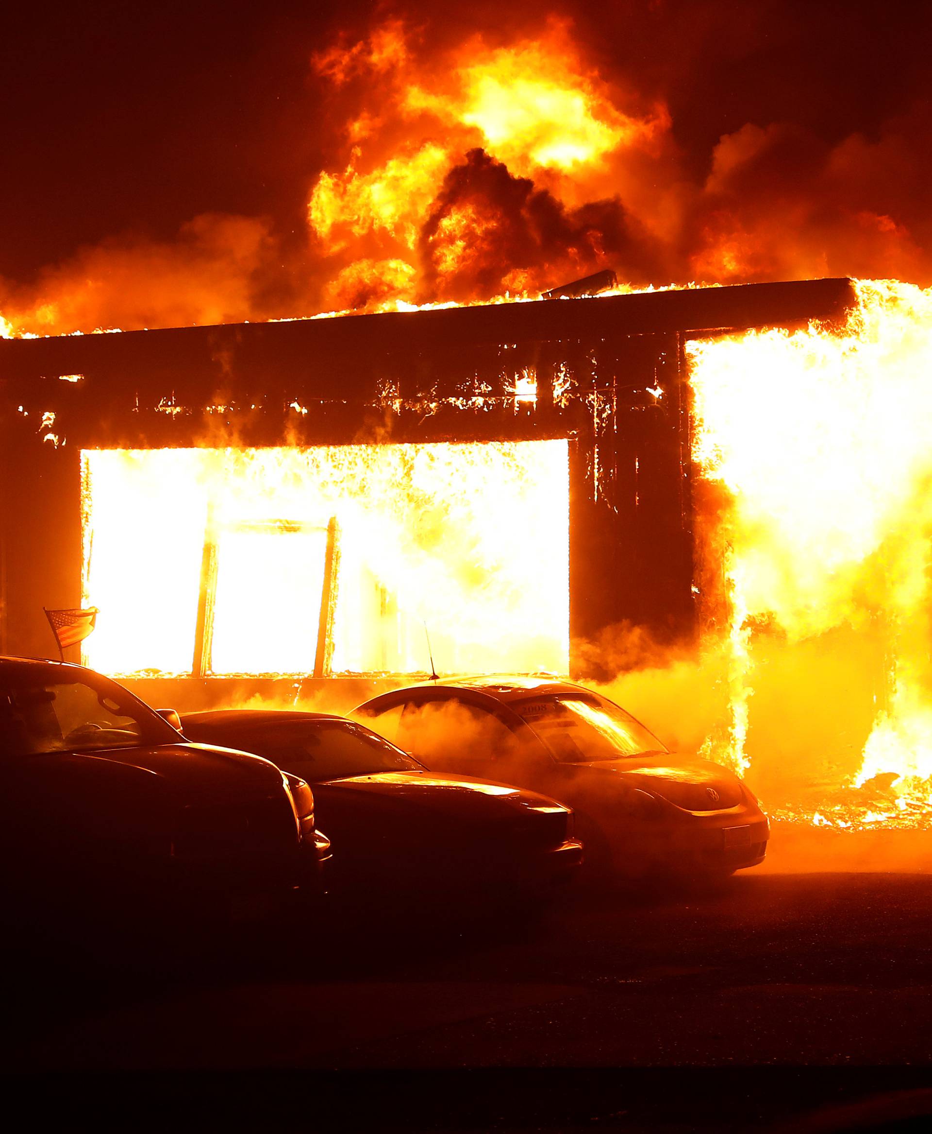 An used car dealership is seen engulfed in flames during the Camp Fire in Paradise, California