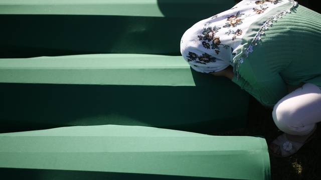 A woman mourns near coffins of her relatives, who are newly identified victims of the 1995 Srebrenica massacre, which are lined up for a joint burial in Potocari near Srebrenica