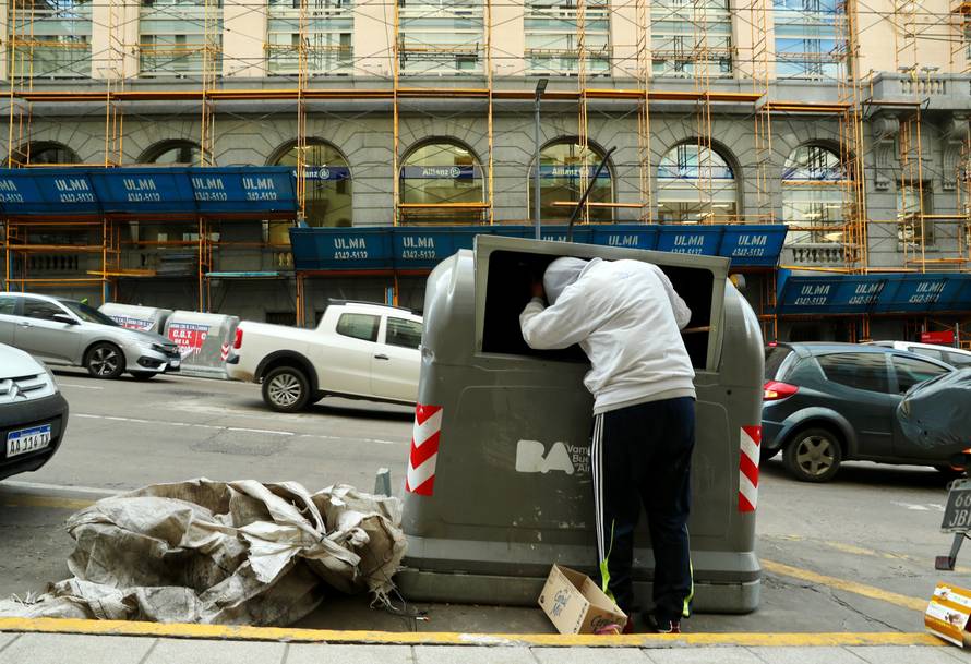 A man looks inside a garbage container on Corrientes avenue in Buenos Aires' financial district