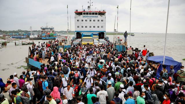 People board an overcrowded ferry as they go home a day before a countrywide lockdown is imposed, in Munshiganj, outskirts of Dhaka