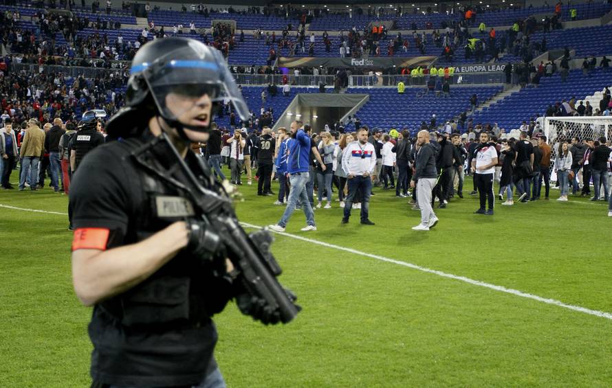 Police officers as Lyon fans invade the pitch and fans clash in the stands