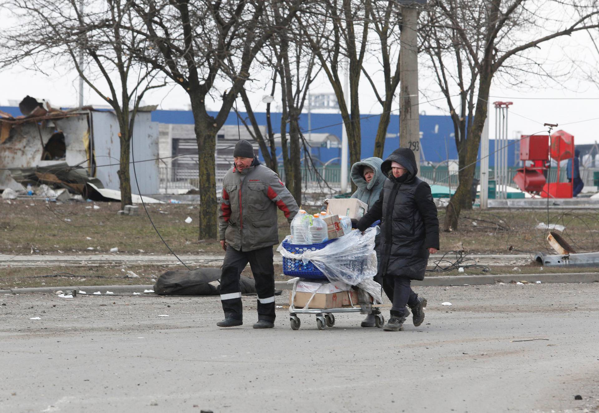 Local residents push a cart in the besieged city of Mariupol