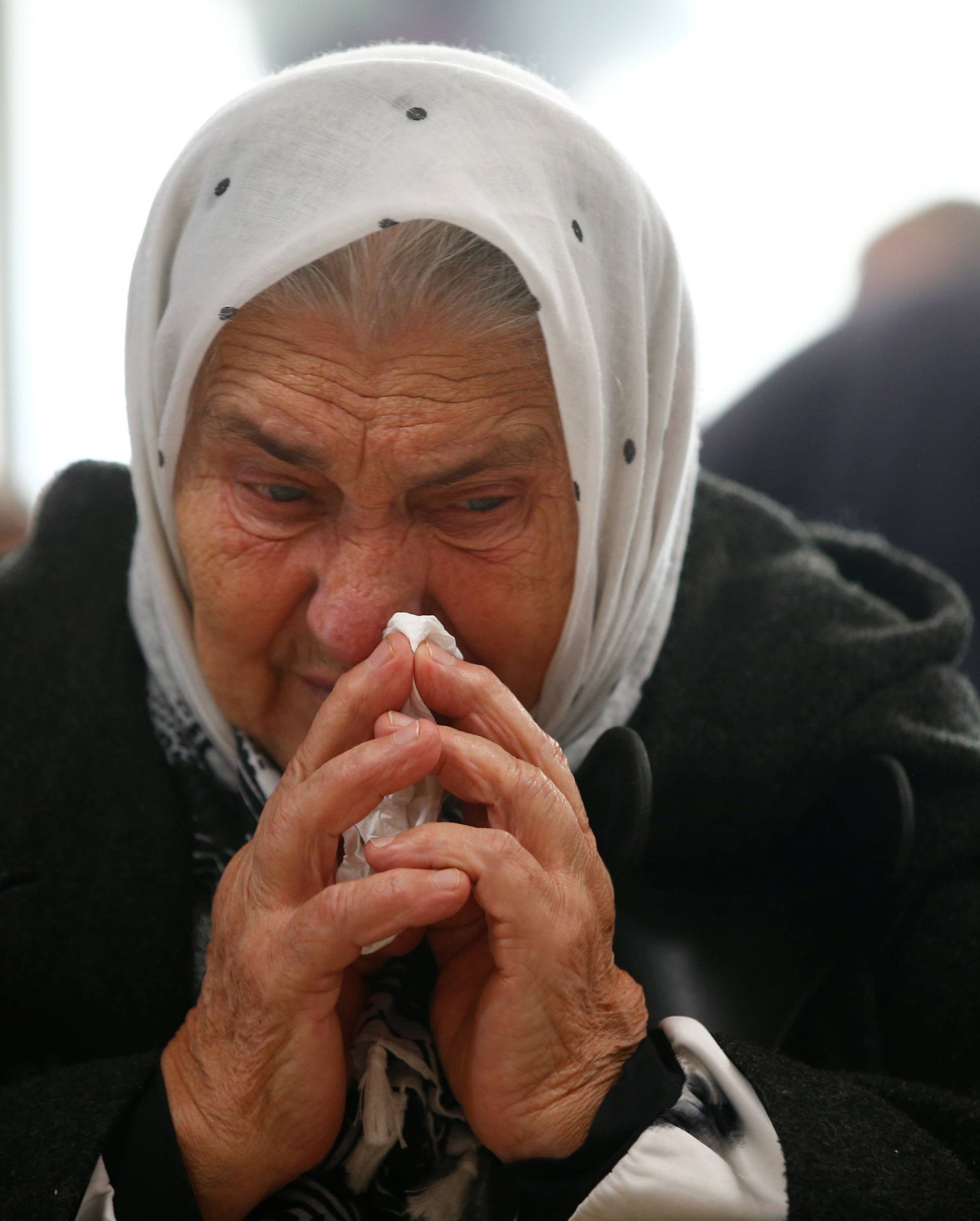 A woman reacts as she watches a television broadcast of the court proceedings of former Bosnian Serb general Ratko Mladic in the Memorial centre Potocari near Srebrenica