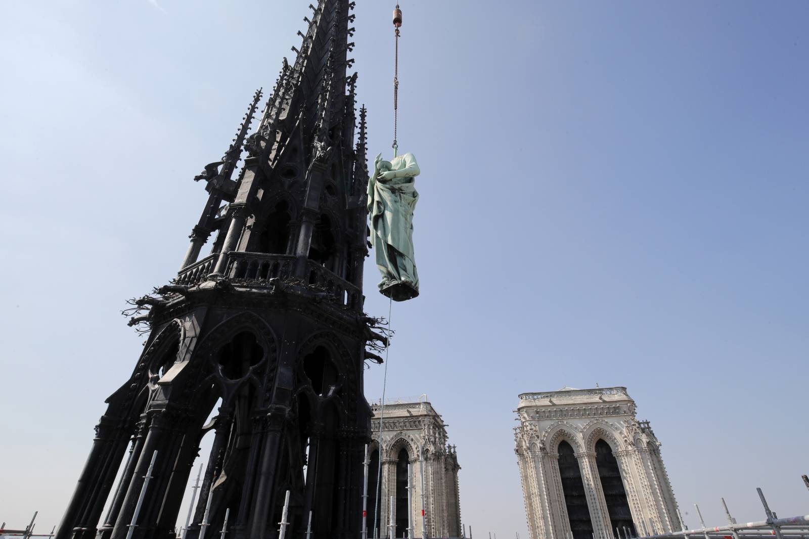 A statue of Saint John is removed from the spire of Notre Dame cathedral by a crane before restoration work, in Paris