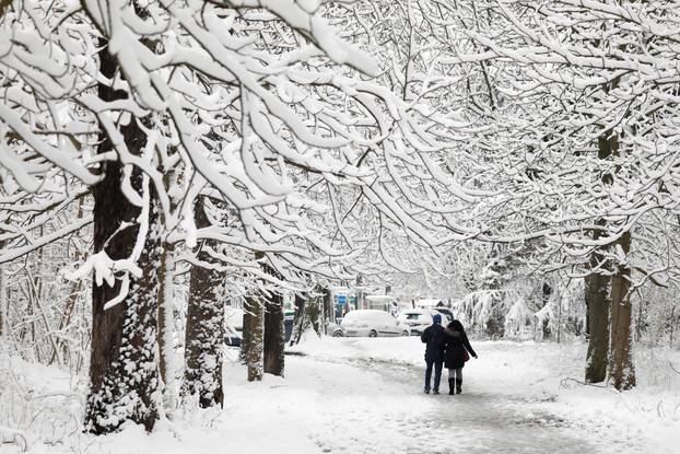 People walk on a snow-covered path in the Bois de Vincennes in Paris, France, as winter weather with snow and freezing temperatures arrive in France